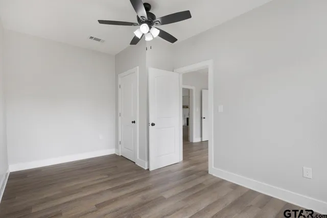 an empty room with wooden floor and ceiling fan