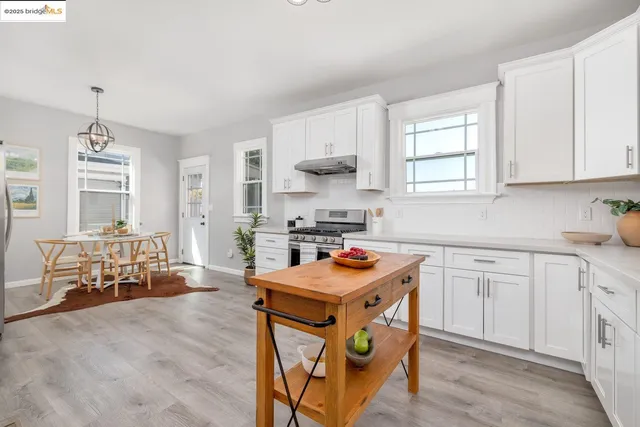 a kitchen with stainless steel appliances granite countertop a stove top oven a sink dishwasher and white cabinets with wooden floor