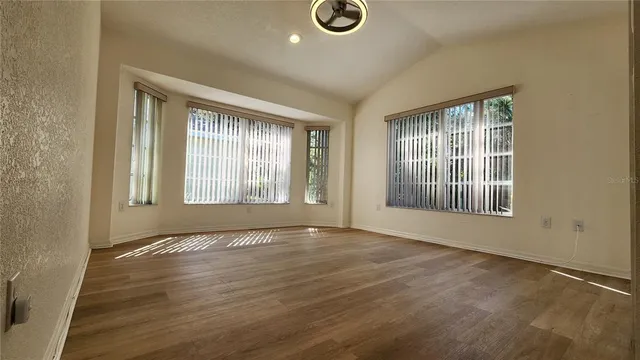 an empty room with wooden floor and windows