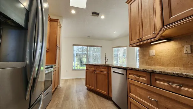 a kitchen with stainless steel appliances granite countertop a refrigerator a sink and wooden cabinets