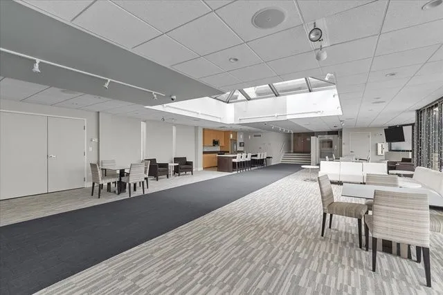 a dining hall with stainless steel appliances granite countertop a stove a sink dishwasher a dining table and chairs with wooden floor