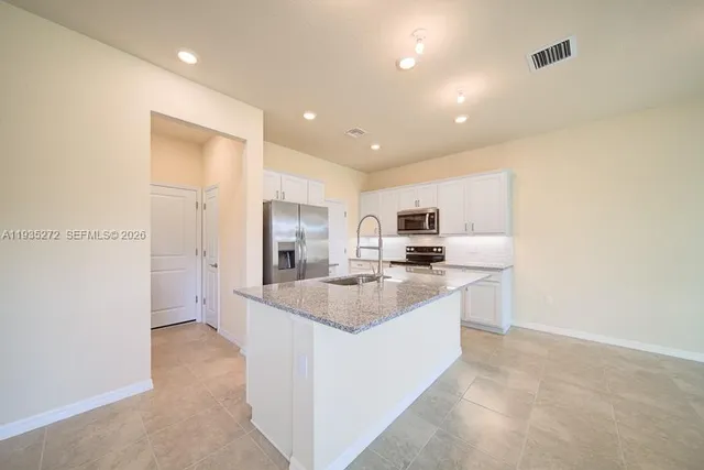 a large kitchen with kitchen island a sink stainless steel appliances and cabinets