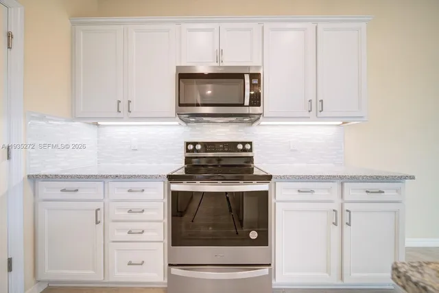 a kitchen with granite countertop white cabinets and stainless steel appliances