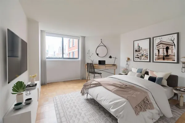 a bedroom with a bed table and a flat screen tv
