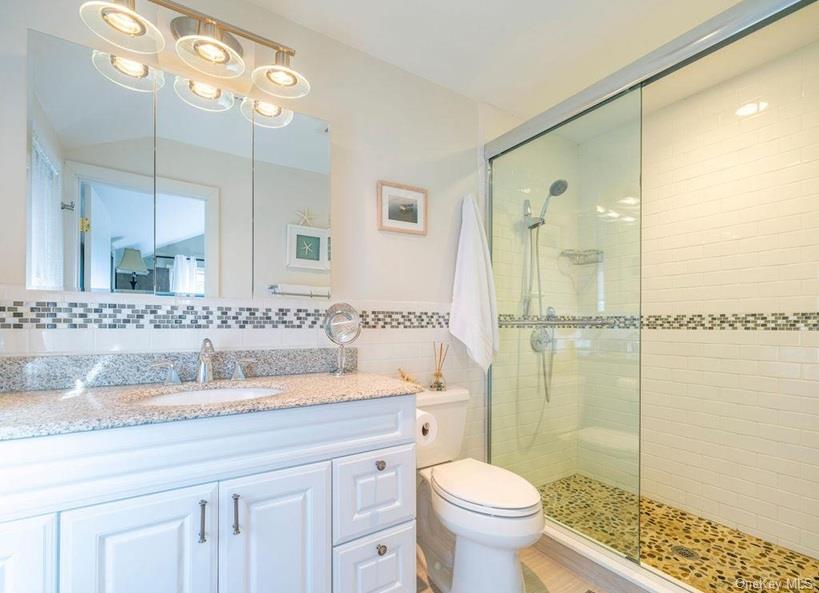 1020 Ruch Lane Southold, NY 11971 - Photo 11 of 35 a bathroom with a granite countertop sink a toilet a mirror and shower