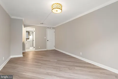 a view of an empty room with wooden floor and window