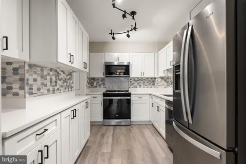 a kitchen with granite countertop a refrigerator sink and white cabinets