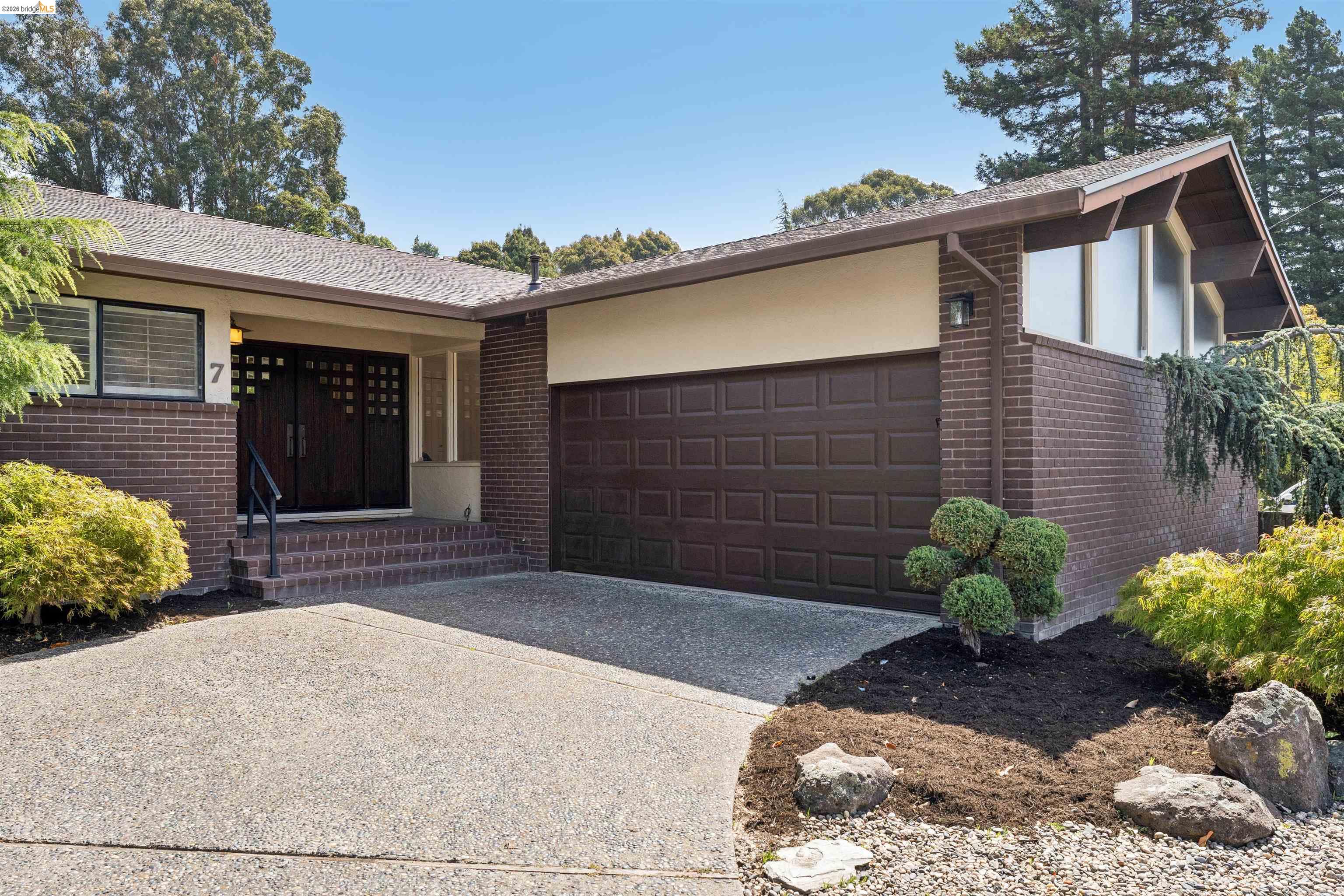 7 Jo Lin Court El Sobrante, CA 94803 - Photo 18 of 99 Brick facade residence featuring a two-car garage, mature landscaping, and an exposed aggregate driveway