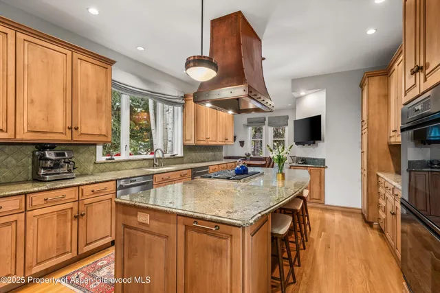a kitchen with stainless steel appliances granite countertop a sink a stove and a wooden floors