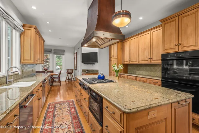 a kitchen with stainless steel appliances granite countertop a sink a stove and a wooden floors
