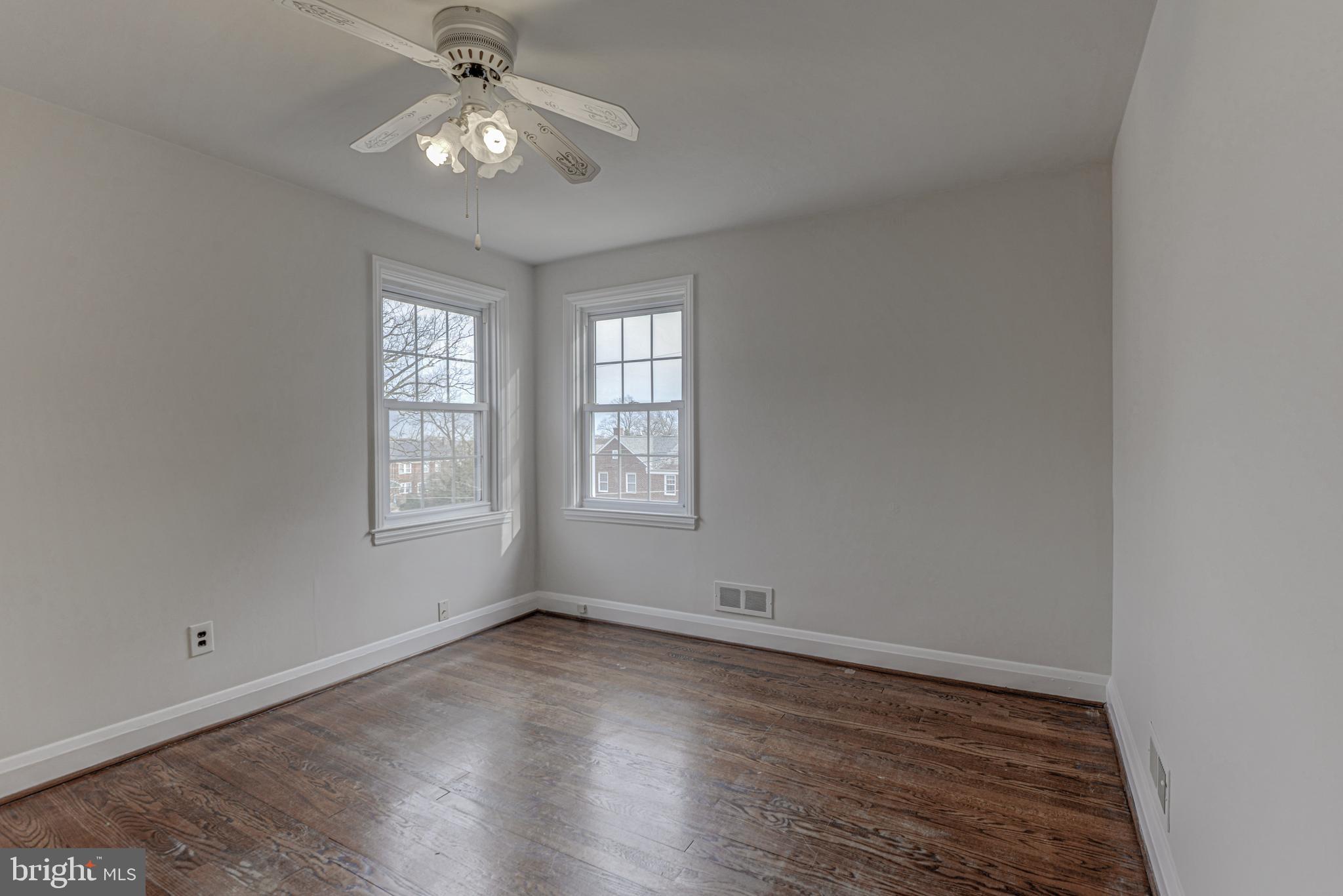 6121 Regent Park Road Baltimore, MD 21228 - Photo 26 of 36 an empty room with wooden floor chandelier fan and windows