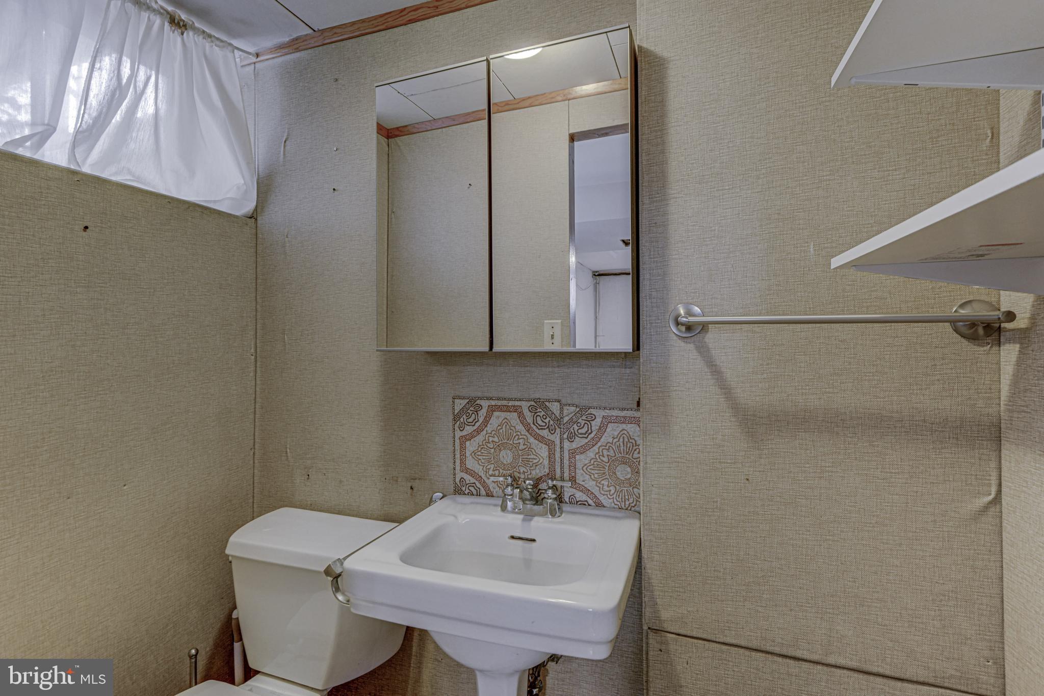 6121 Regent Park Road Baltimore, MD 21228 - Photo 32 of 36 a bathroom with a sink a toilet and mirror