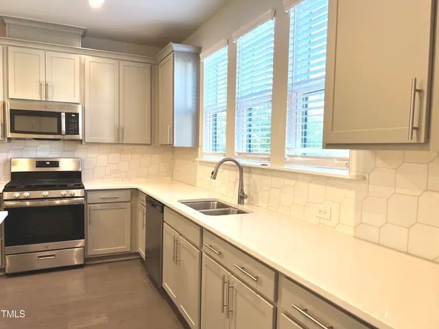 a kitchen with stainless steel appliances granite countertop a stove a sink and a refrigerator