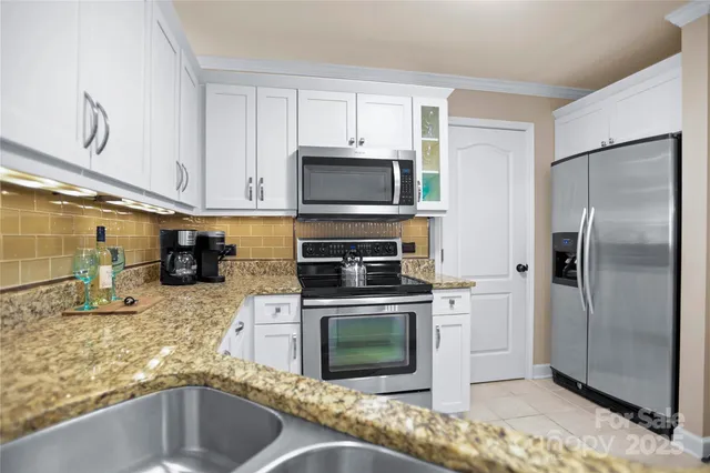 a kitchen with granite countertop a refrigerator stove and microwave