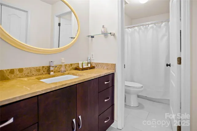 a bathroom with a granite countertop sink a toilet and a mirror