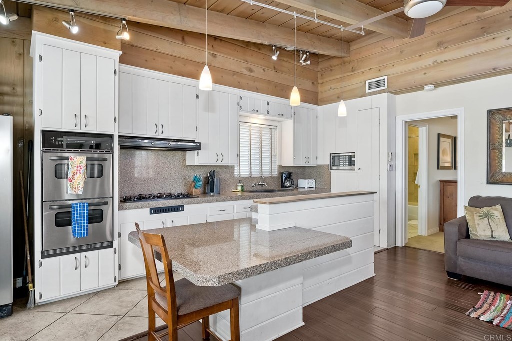 367 Beech Avenue Carlsbad, CA 92008 - Photo 14 of 23 a kitchen with kitchen island granite countertop a table chairs microwave and cabinets