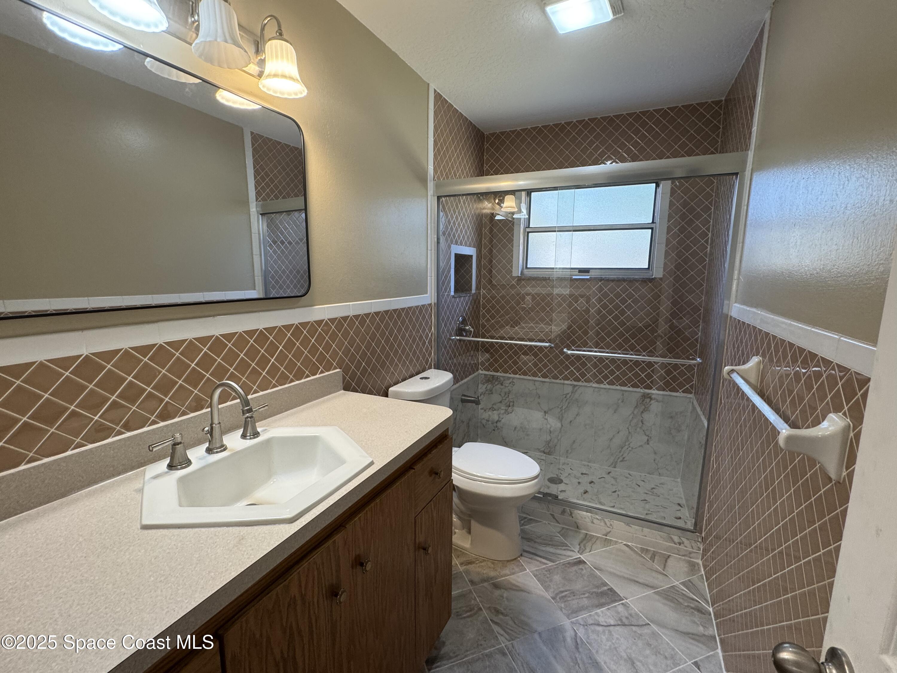 997 Beacon Road Rockledge, FL 32955 - Photo 9 of 18 a bathroom with a sink a toilet a mirror and shower