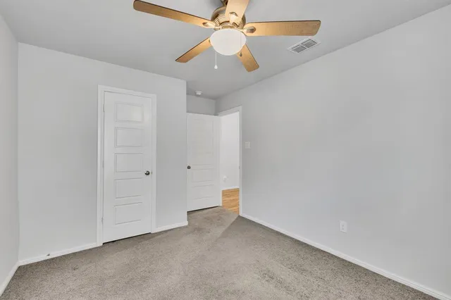 an empty room with a ceiling fan and a fan