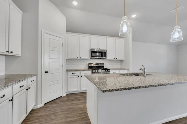a kitchen with granite countertop a sink a counter space appliances and cabinets