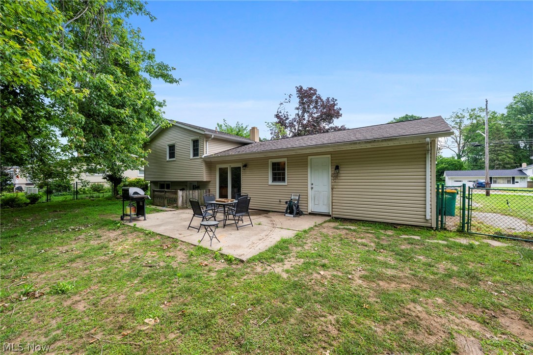 6472 Southgrove Road Mentor, OH 44060 - Photo 32 of 37 Rear exterior featuring a concrete patio, mature perimeter trees, and a chain-link fence