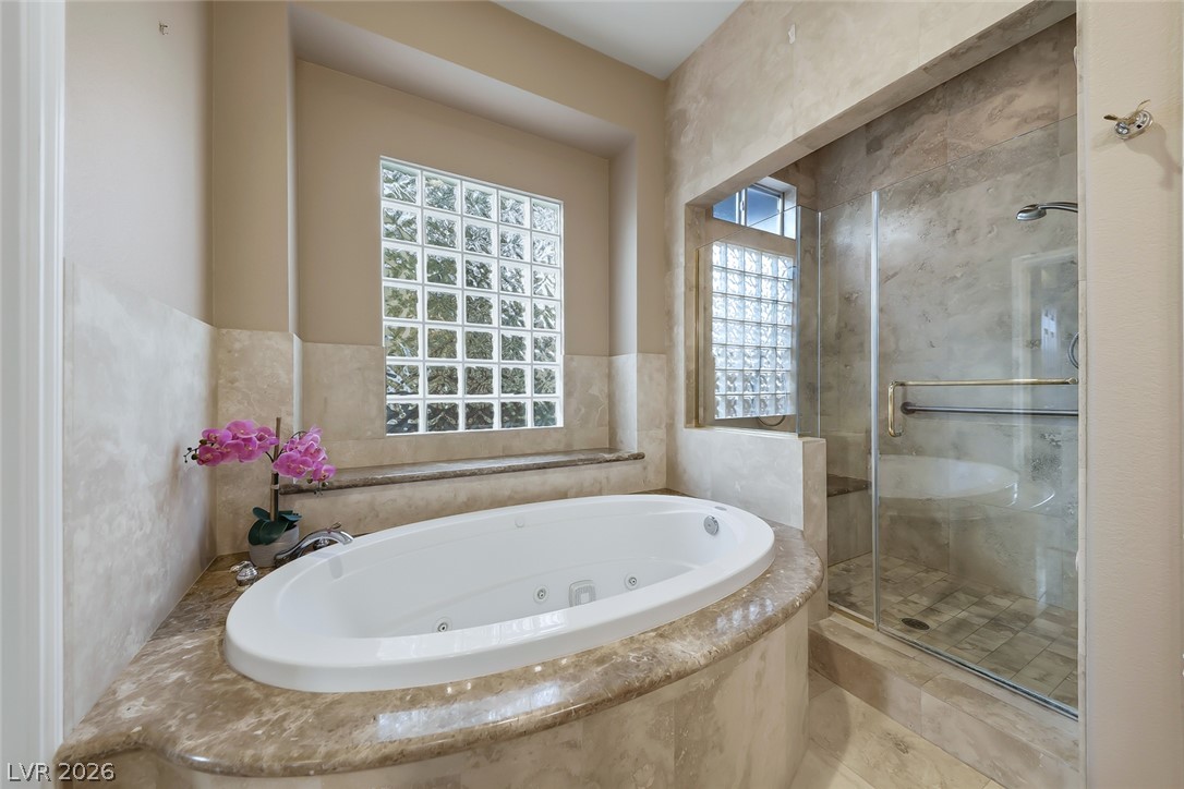 1104 Norellat Road Henderson, NV 89011 - Photo 29 of 52 An elegant soaking tub set in stone tile sits beneath natural light from glass block windows.