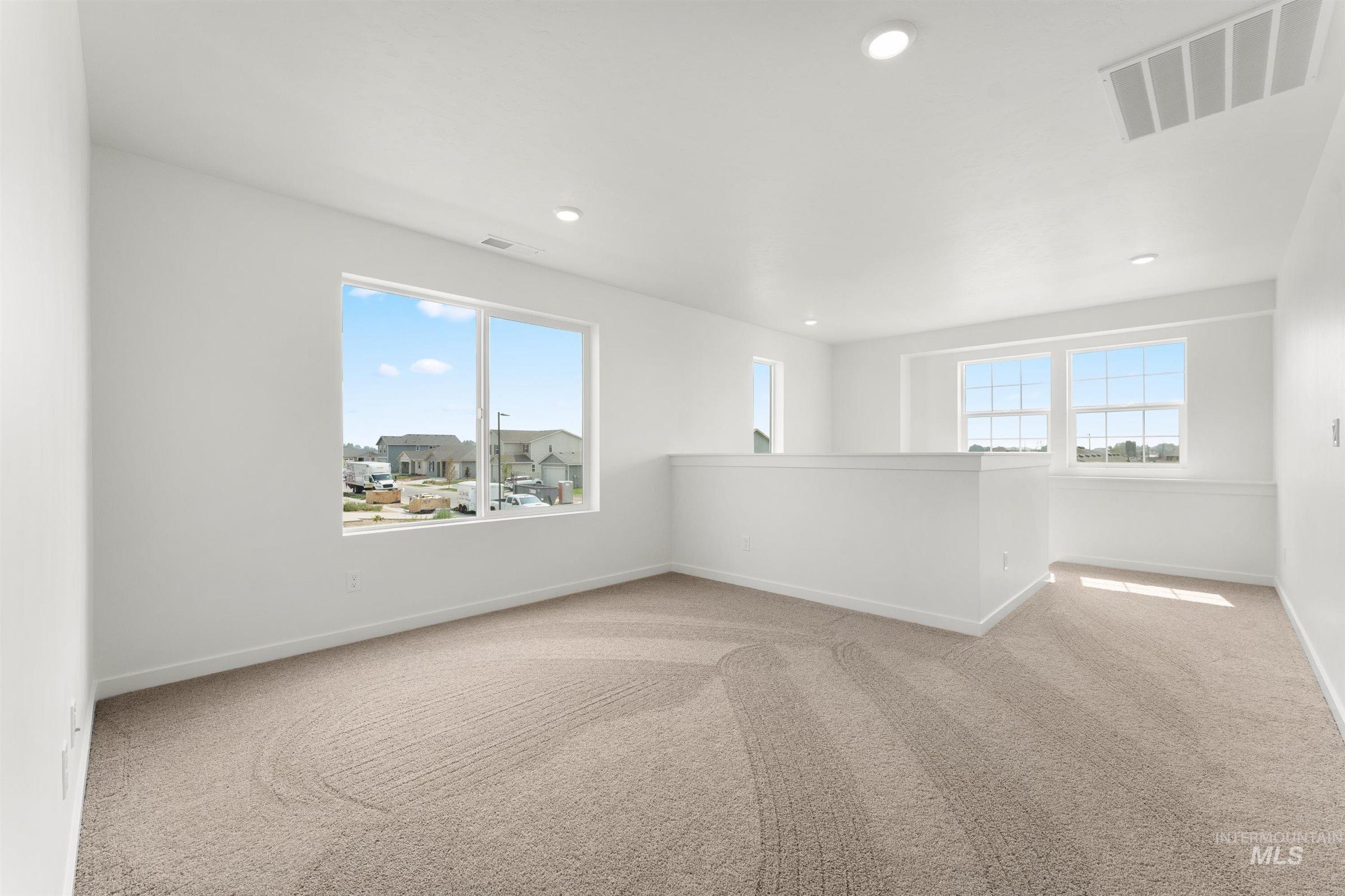 1076 East Exploration Drive Kuna, ID 83634 - Photo 13 of 29 Empty room featuring light colored carpet, healthy amount of natural light, and recessed lighting