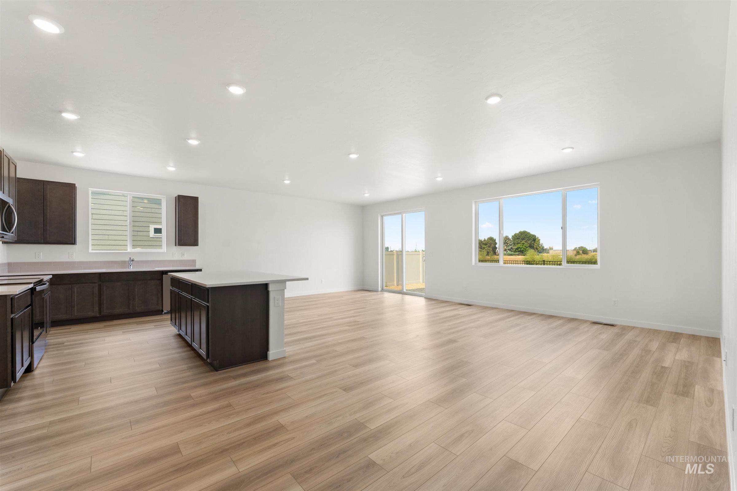 1076 East Exploration Drive Kuna, ID 83634 - Photo 27 of 29 Kitchen with a center island, dark brown cabinets, appliances with stainless steel finishes, open floor plan, and recessed lighting