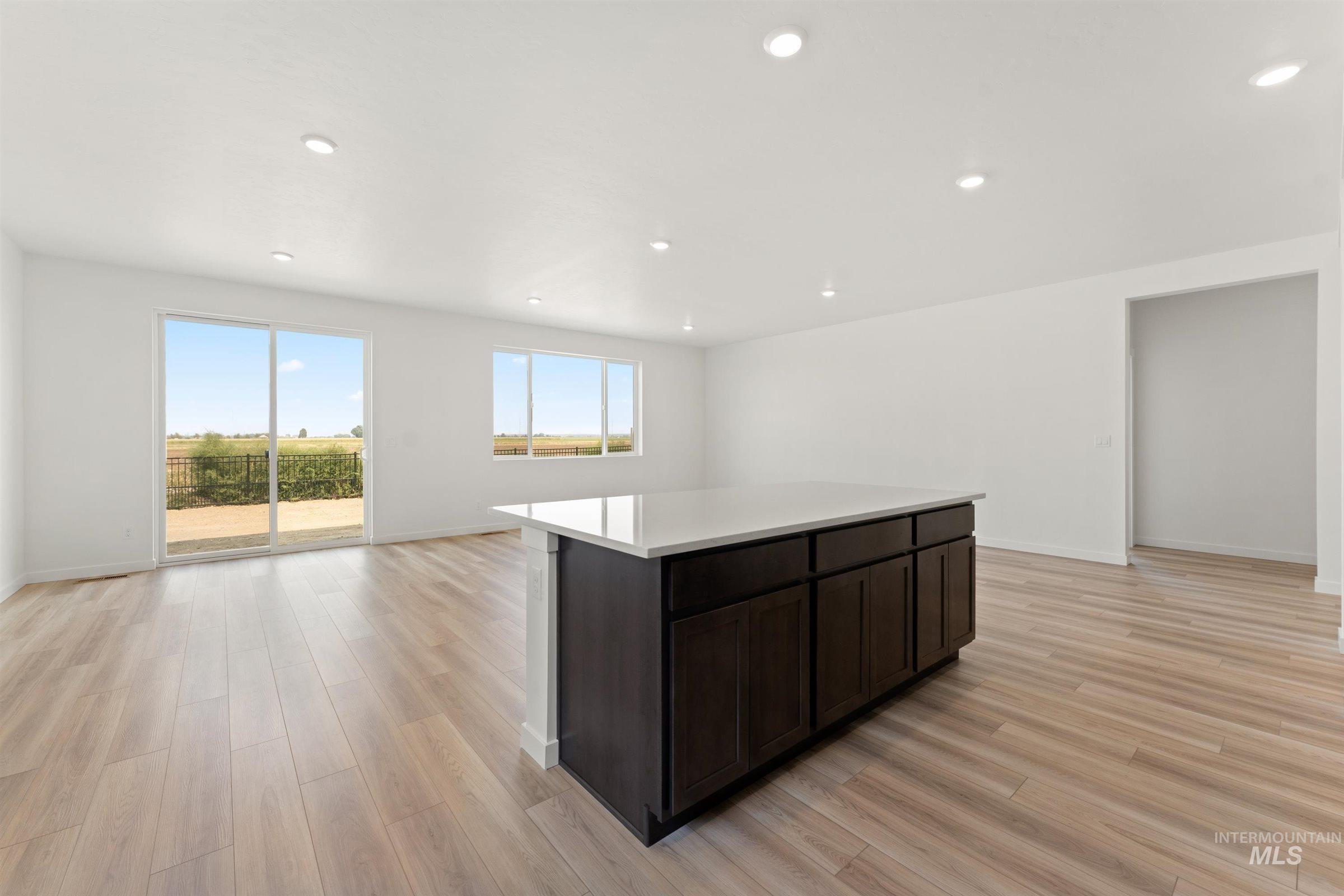 1076 East Exploration Drive Kuna, ID 83634 - Photo 29 of 29 Kitchen with dark brown cabinetry, open floor plan, a kitchen island, recessed lighting, and light wood-style flooring