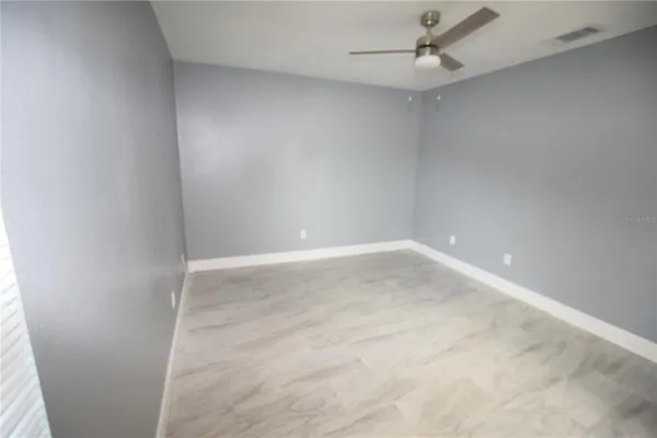 an empty room with a ceiling fan and carpet