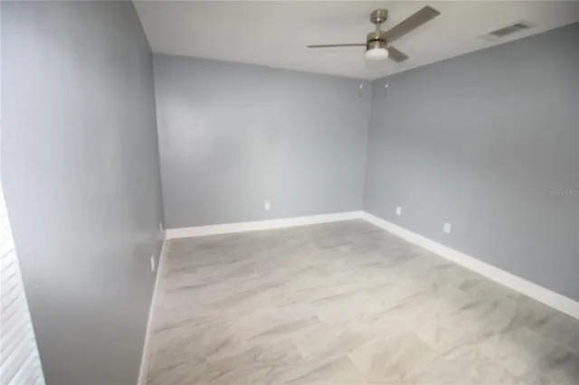 an empty room with a ceiling fan and carpet