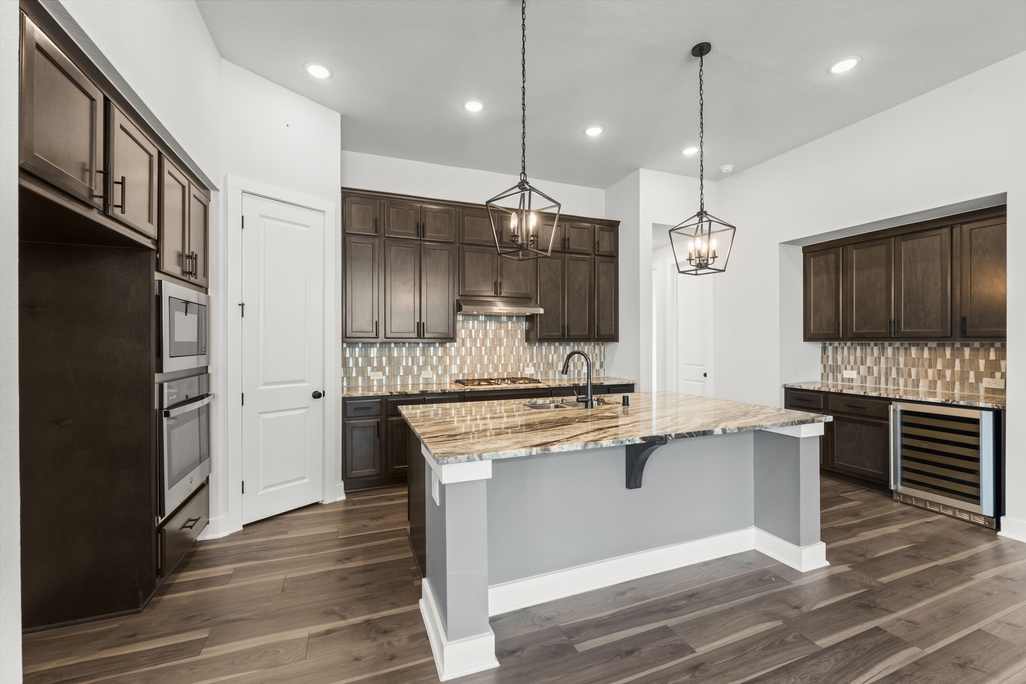 17151 Sandstone Street Conroe, TX 77302 - Photo 11 of 38 a kitchen with stainless steel appliances kitchen island granite countertop a refrigerator a stove and a wooden floor