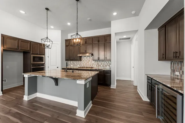 a kitchen with stainless steel appliances granite countertop a sink a stove and a wooden floors