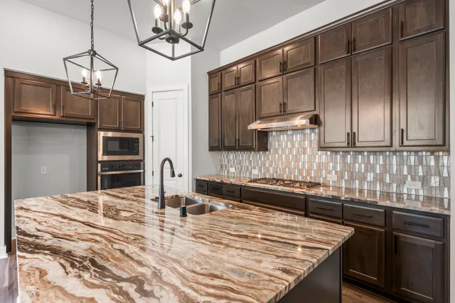 a kitchen with stainless steel appliances granite countertop a sink refrigerator and cabinets