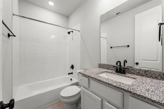 a bathroom with a granite countertop sink a toilet and a bathtub
