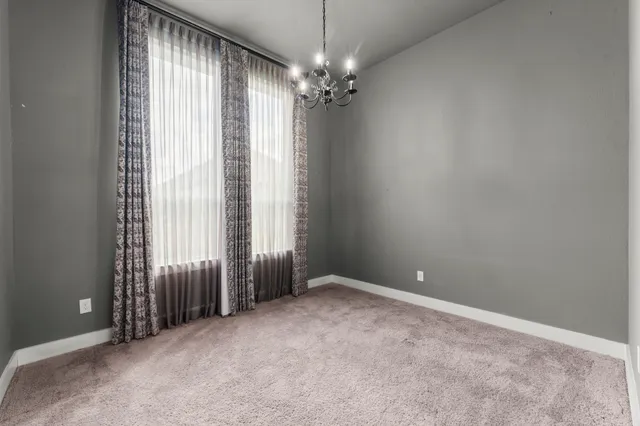 an empty room with windows and chandelier fan