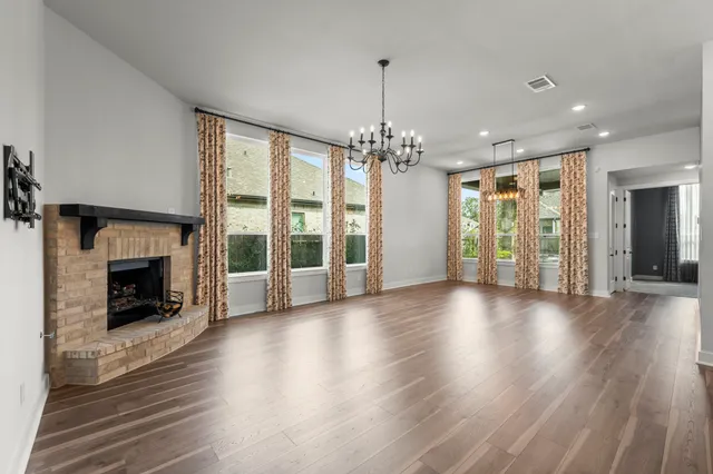 a view of an empty room with wooden floor fireplace and a window