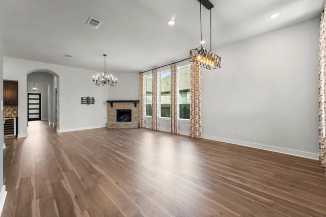 an empty room with wooden floor fireplace and windows