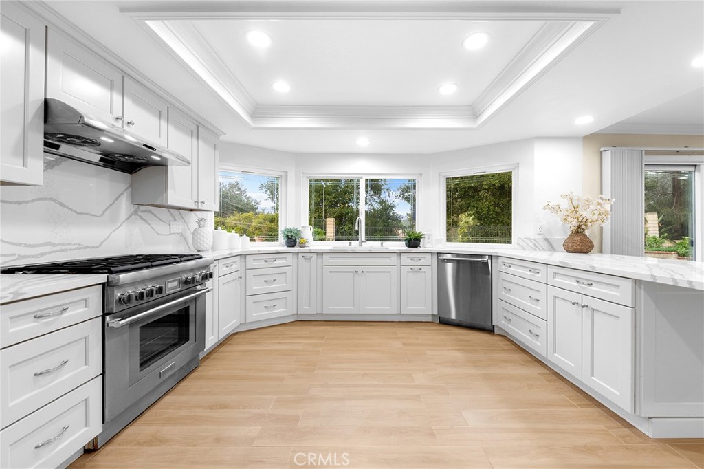 20329 Rim Ridge Road Walnut, CA 91789 - Photo 19 of 46 a white kitchen with stainless steel appliances granite countertop a stove a sink dishwasher and white cabinets with wooden floor