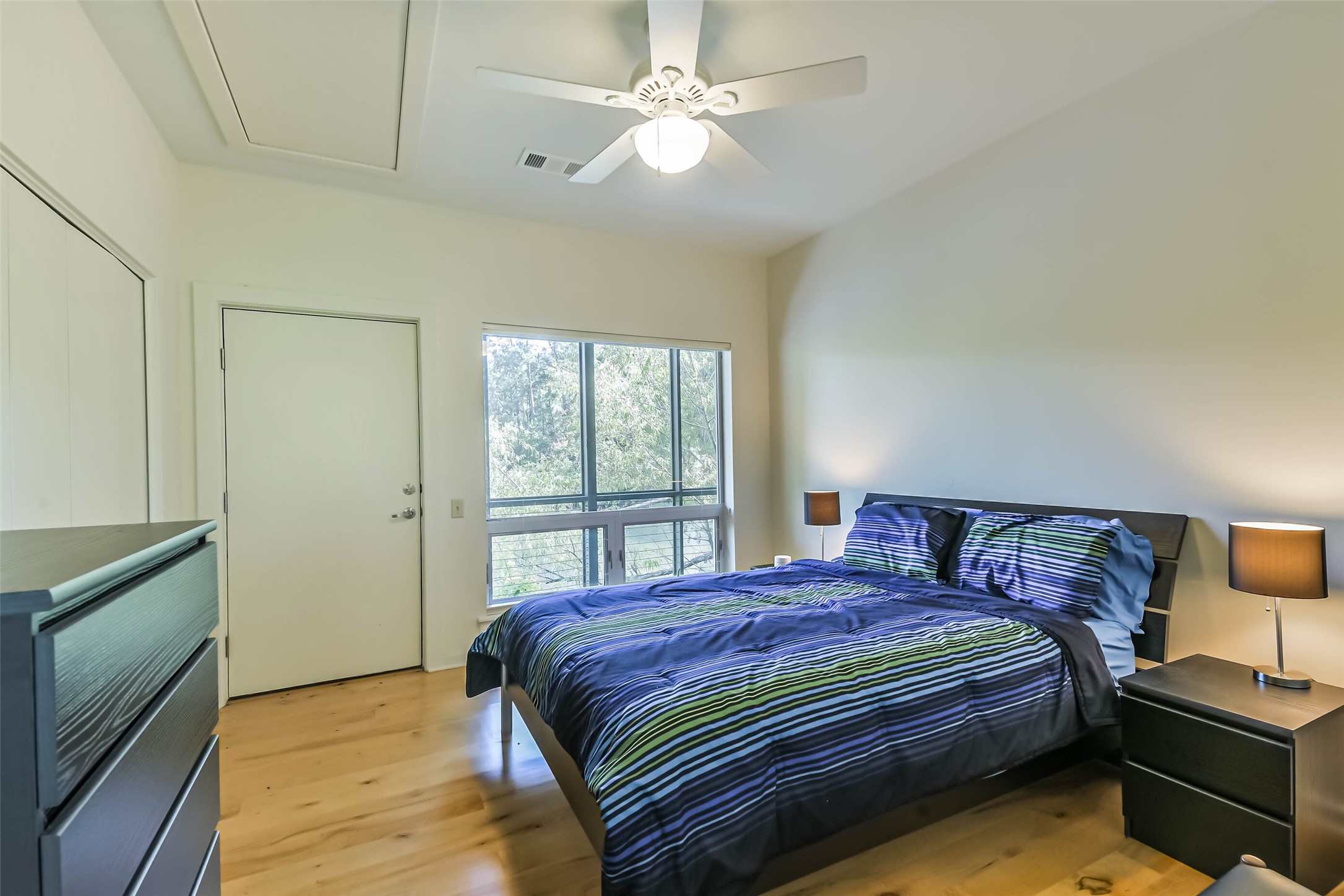 88 Raccoon Ramble Cleveland, TX 77327 - Photo 33 of 43 Bright and inviting bedroom featuring a large window with serene views, complemented by modern furnishings and a ceiling fan.