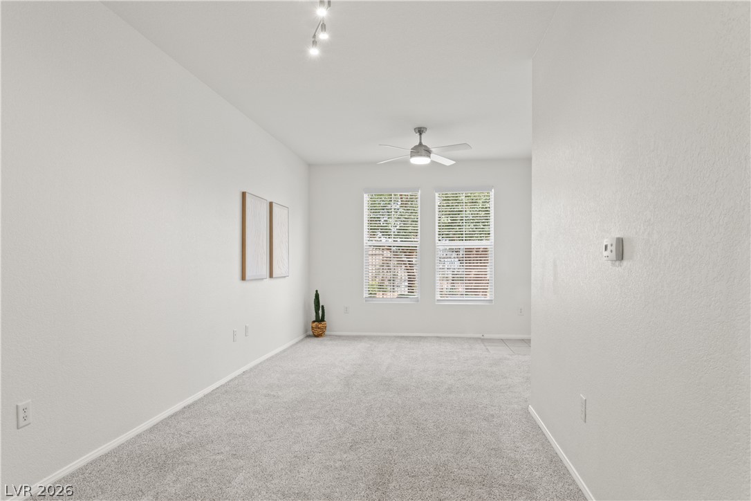 10550 West Alexander Road, Unit 1025 Las Vegas, NV 89129 - Photo 13 of 42 A well-lit, neutral-toned living space offers comfort with carpet flooring and window blinds for privacy.