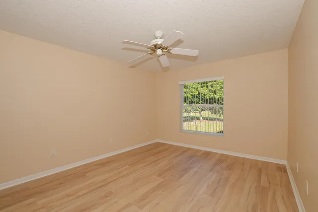 an empty room with a window and a fan