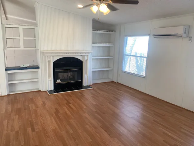 a view of empty room with a fireplace and wooden floor
