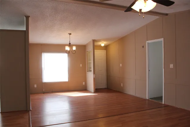 a view of an empty room with window chandelier fan and fire place
