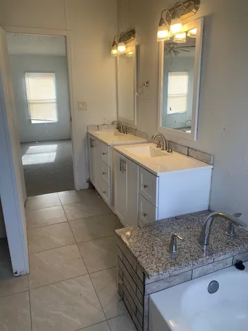 a bathroom with a granite countertop sink a mirror and a bathtub