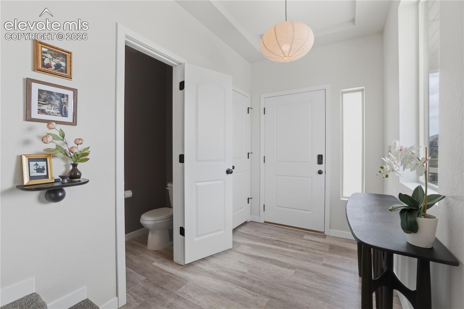 6008 Ashmore Road Colorado Springs, CO 80927 - Photo 16 of 48 Entryway featuring wood-finish flooring, a white paneled entry door, and a tall side window