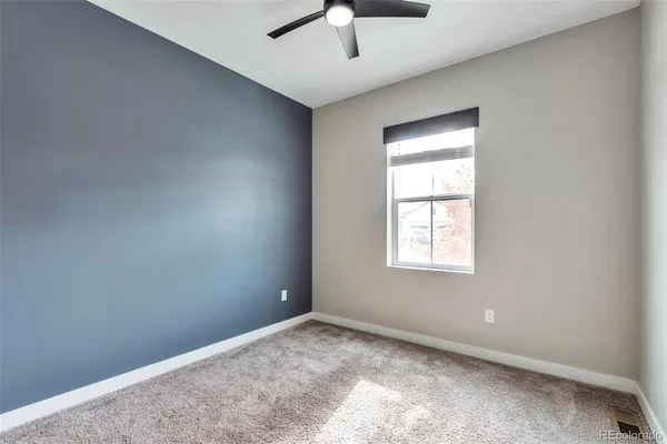 an empty room with a chandelier fan and windows