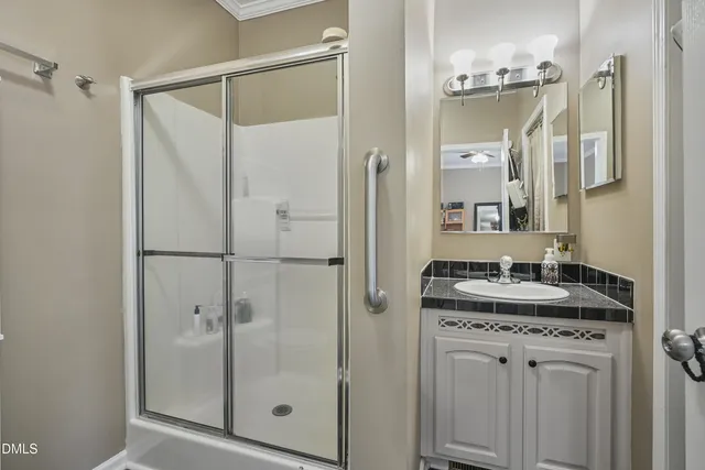 a bathroom with a granite countertop sink a mirror and a shower