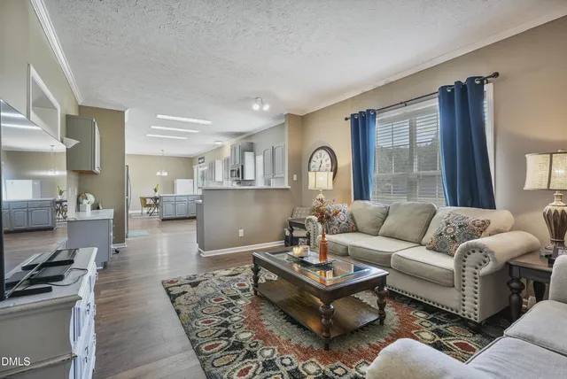 a living room with furniture wooden floor and a kitchen view