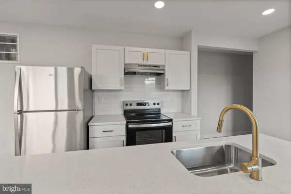 a kitchen with stainless steel appliances a refrigerator sink and white cabinets