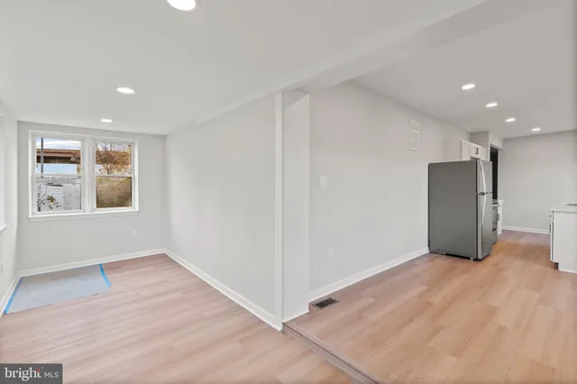 a view of an empty room with window and wooden floor